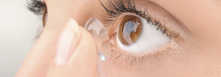 Close-up view of a person applying a contact lens with careful placement on the eye.